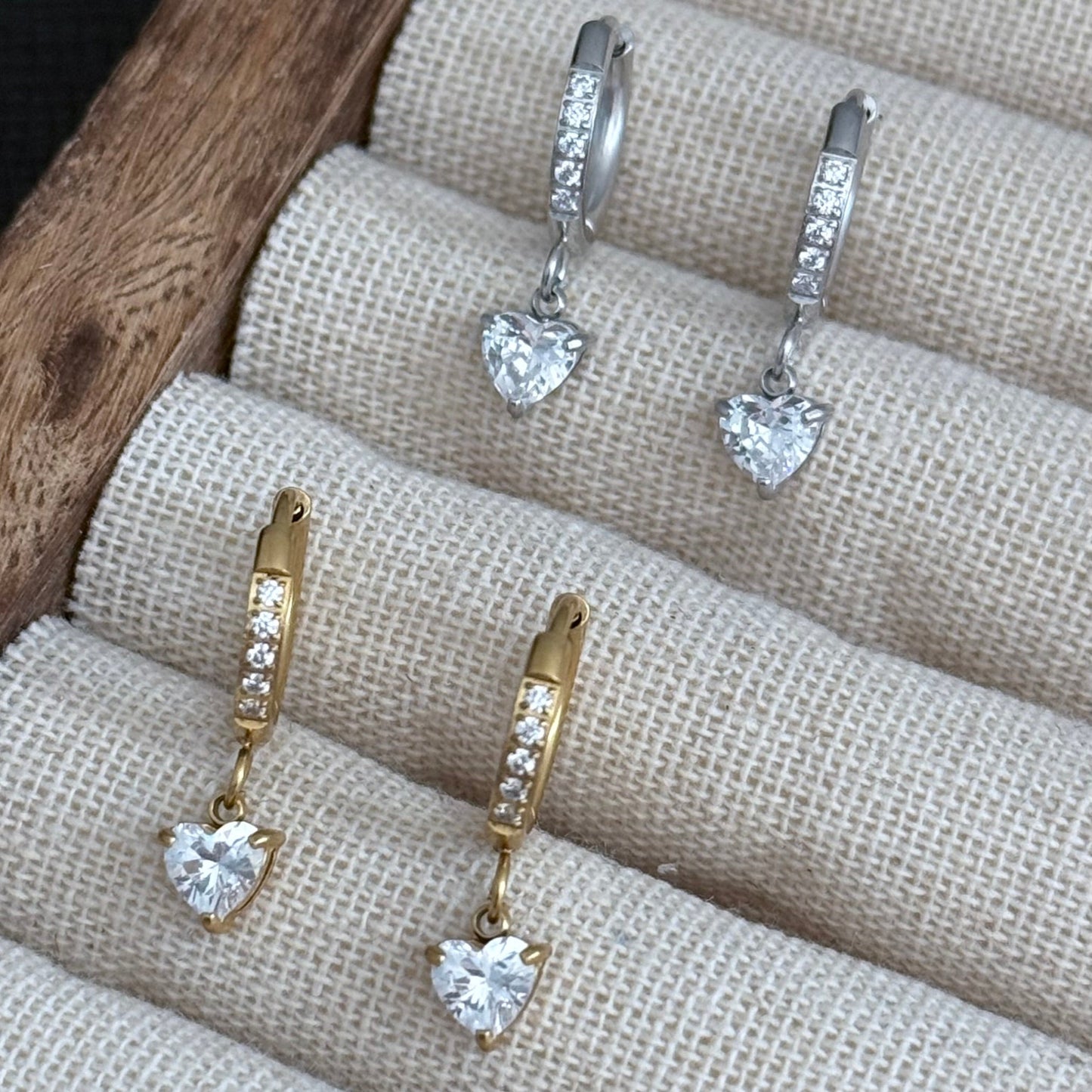 Pair of gold and silver heart-shaped earrings on a textured surface.