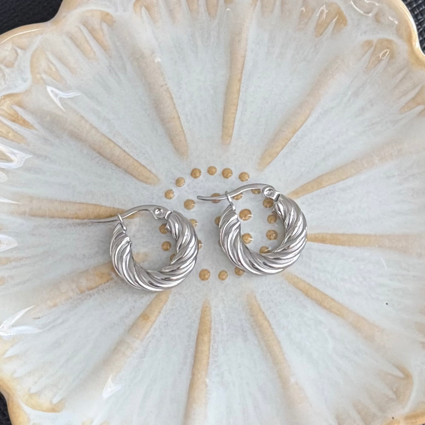 Silver hoop earrings on a decorative white plate with gold accents