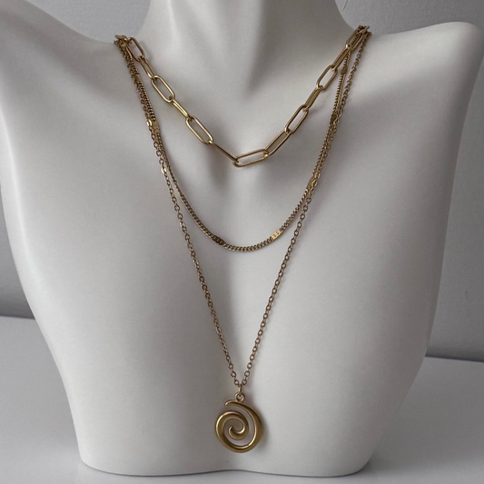 Gold chain necklace with a spiral pendant on a mannequin bust.