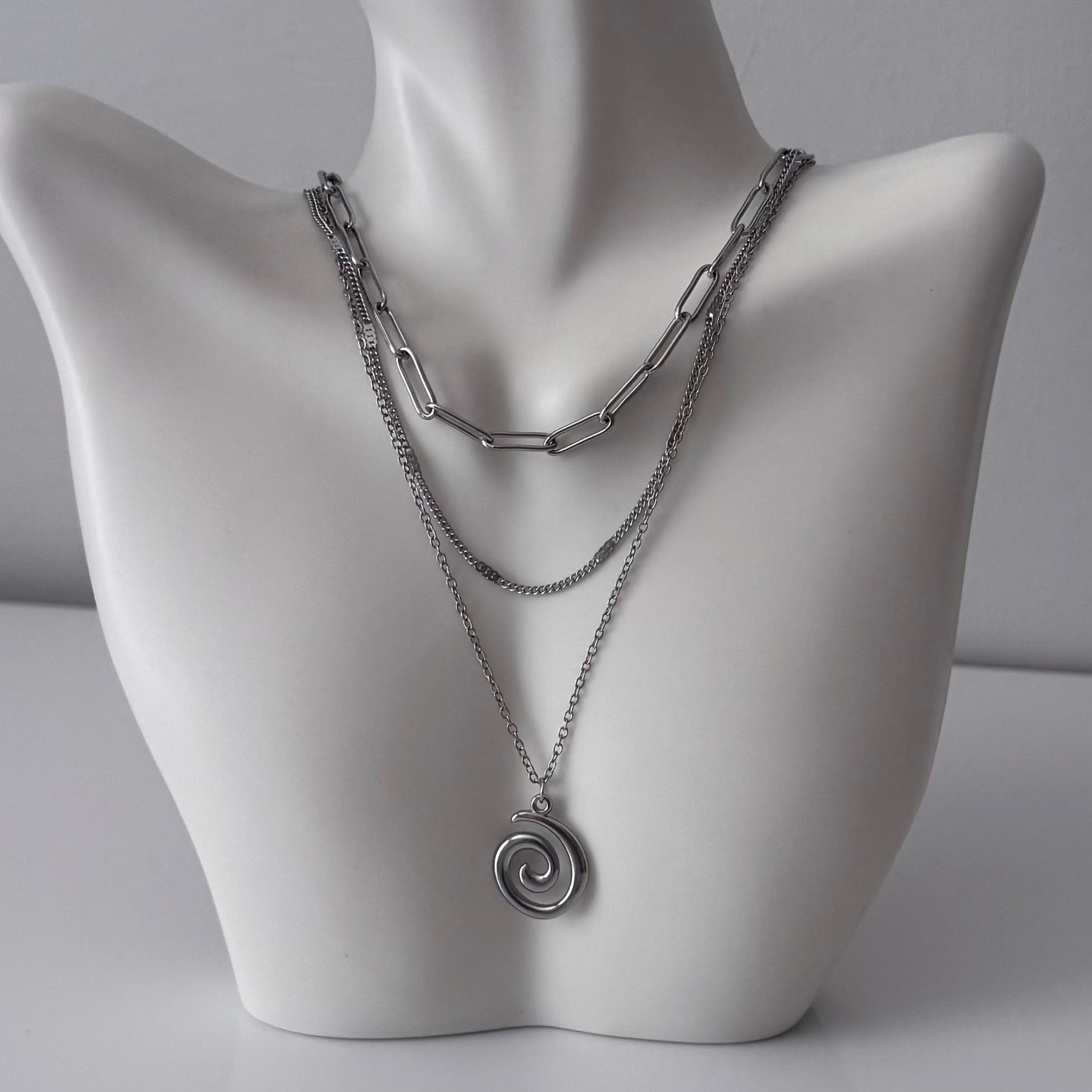 Silver chain necklace with a spiral pendant on a mannequin bust against a gray background
