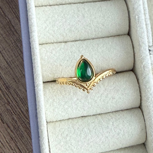 Gold ring with a green gemstone on a white jewelry box