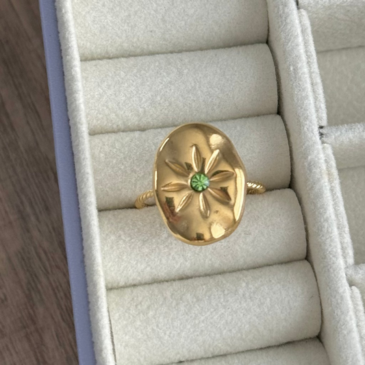Gold ring with a green gemstone in a jewelry box