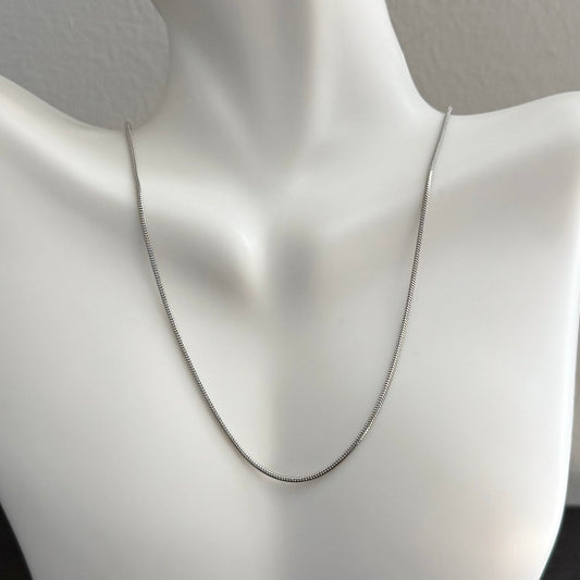 Silver chain necklace on a mannequin bust against a neutral background