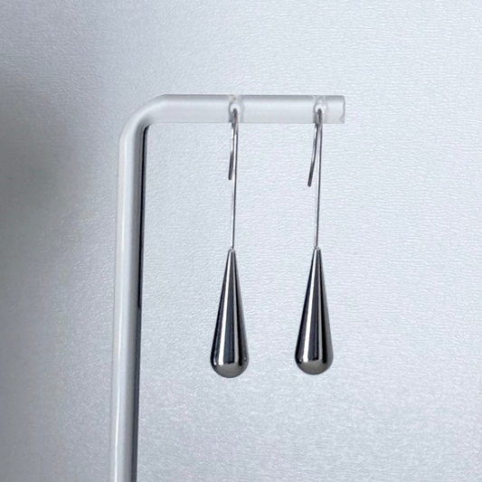 Pair of silver teardrop earrings on a white stand against a light gray background