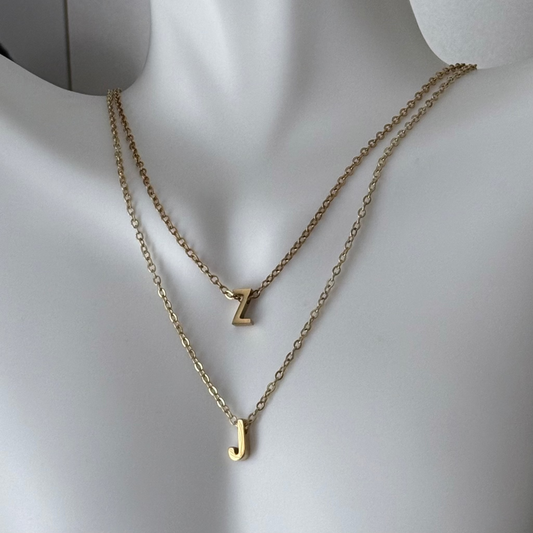 Gold necklaces with letter 'Z' and 'J' pendants on a mannequin.