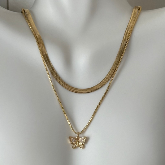Gold necklace with a butterfly pendant on a mannequin.