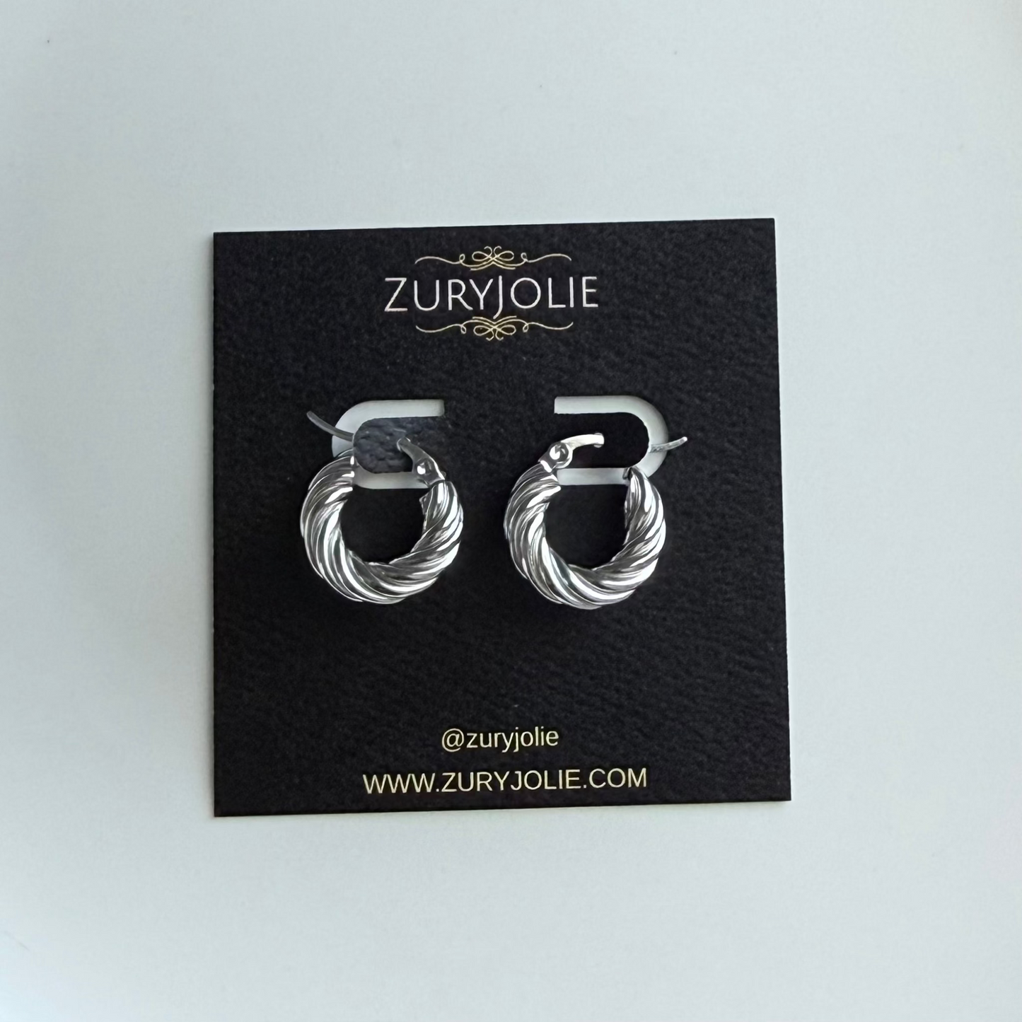 Silver hoop earrings on a Zury Jolie branded card against a light gray background