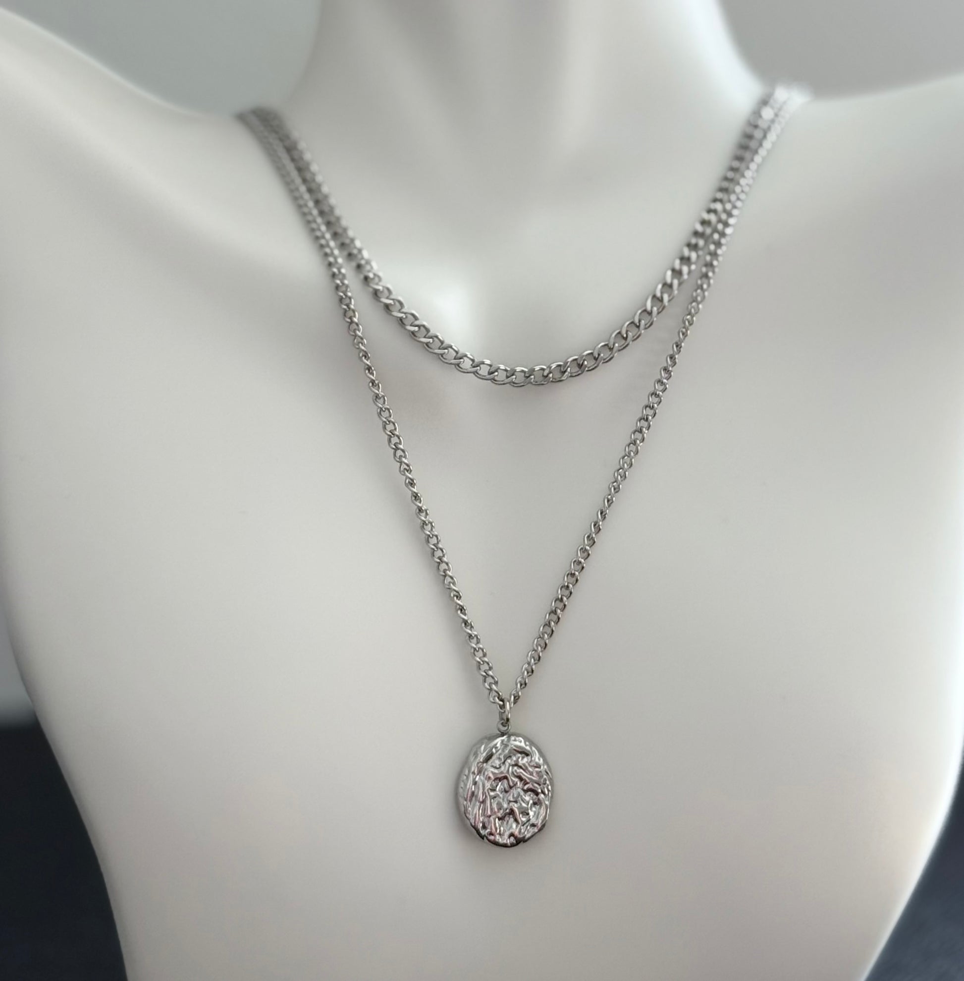 Silver chain necklace with a pendant on a mannequin bust.