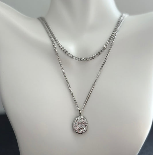 Silver chain necklace with a pendant on a mannequin bust.