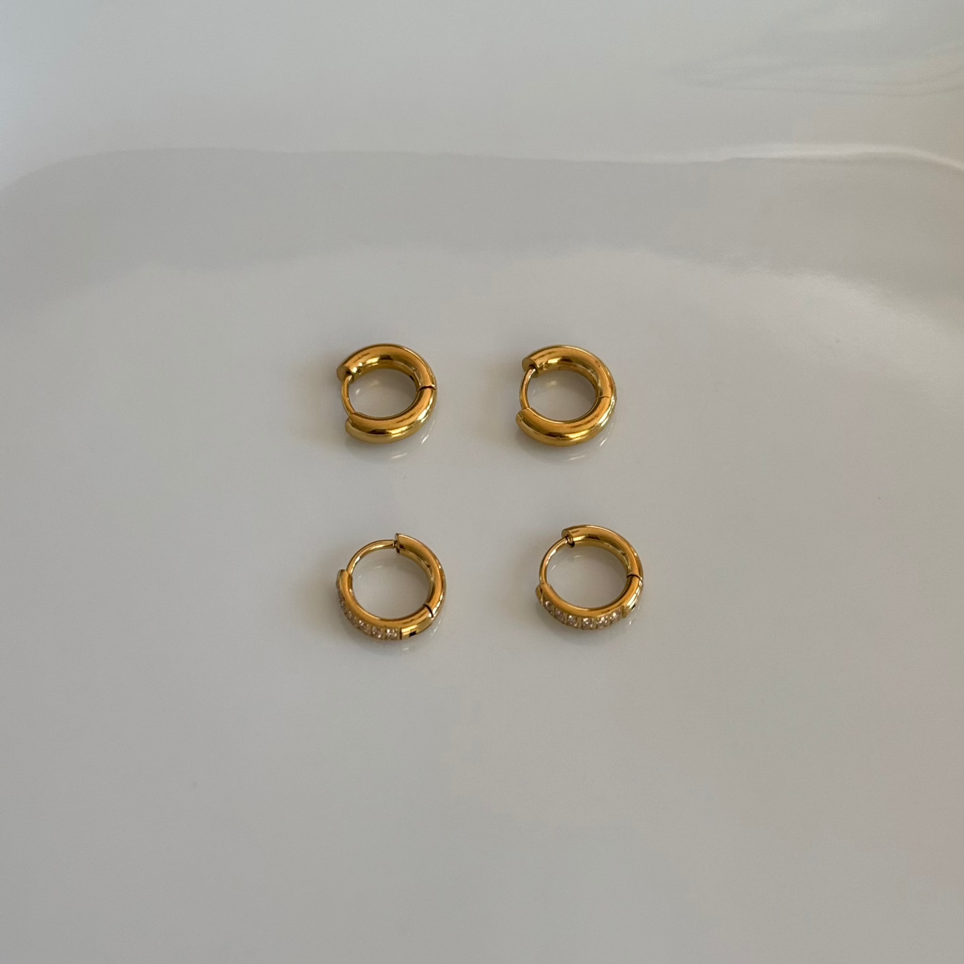 Close up of Two pairs of Huggie Hoops 18K Gold Plated over stainless steel. 