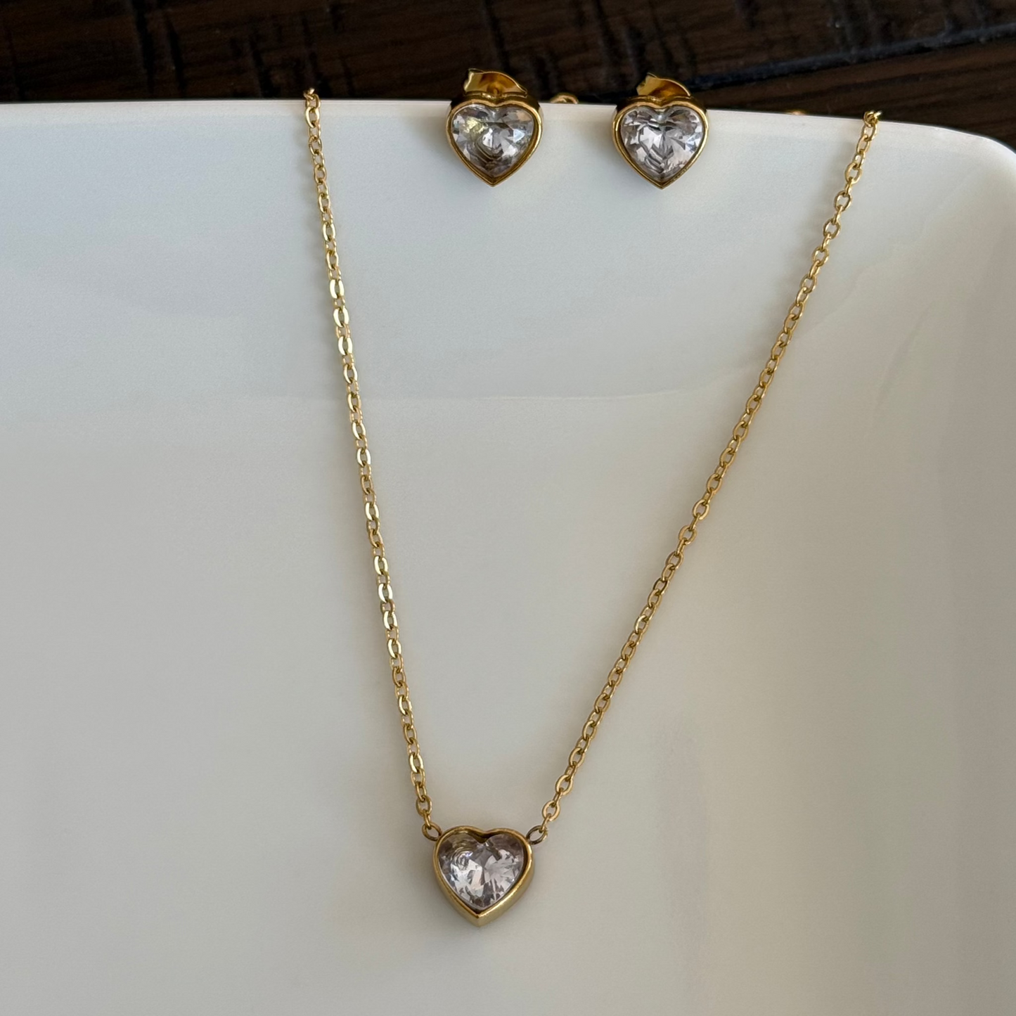 Close up of gold necklace with heart zircon pendant and a pair of zircon heart earring studs