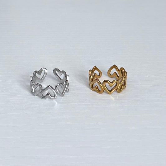 Two heart-shaped rings, one silver and one gold, on a light gray background.