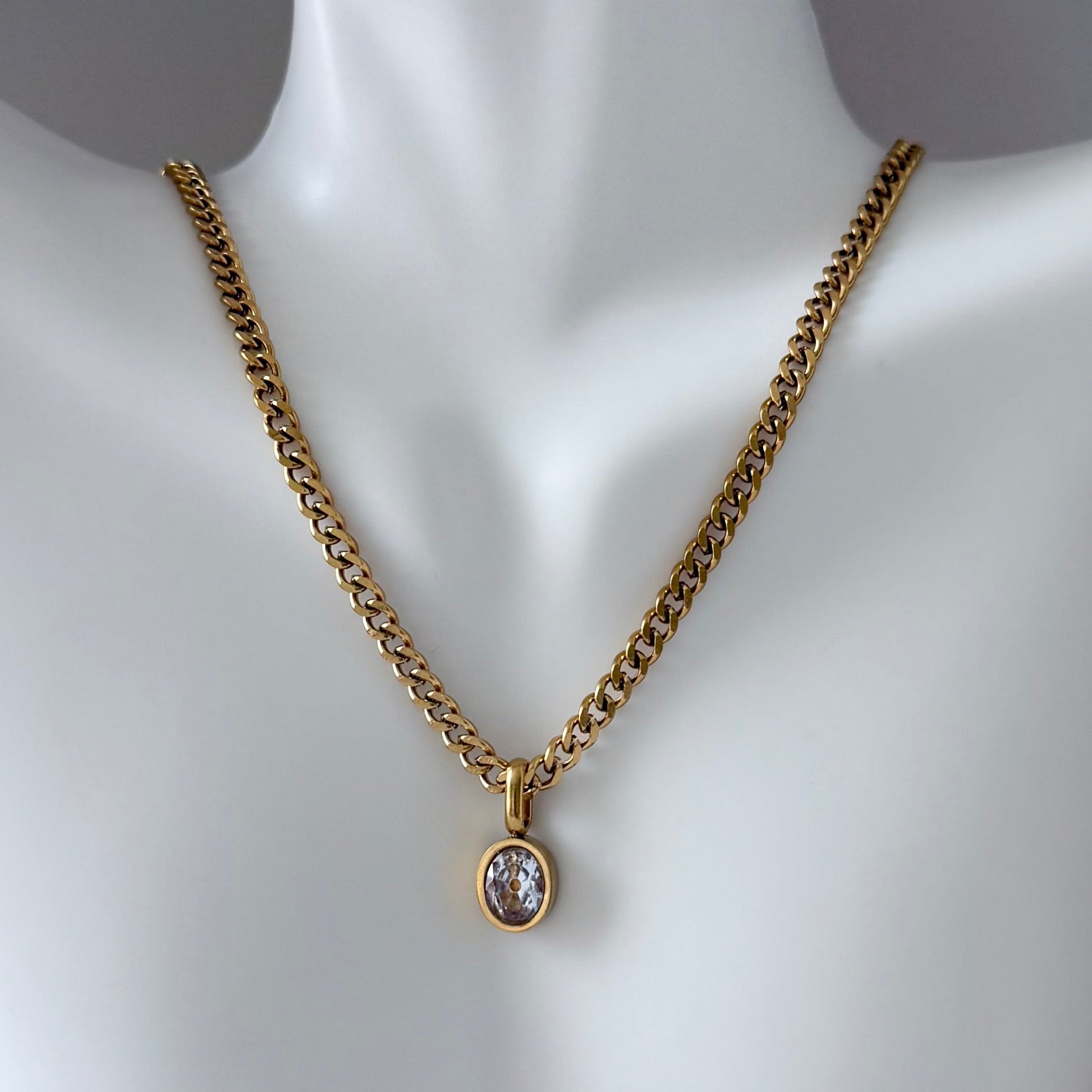 Gold chain necklace with a pendant on a mannequin