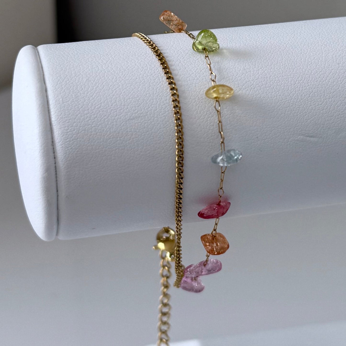 Bracelet with colorful gemstones on a white cylindrical stand