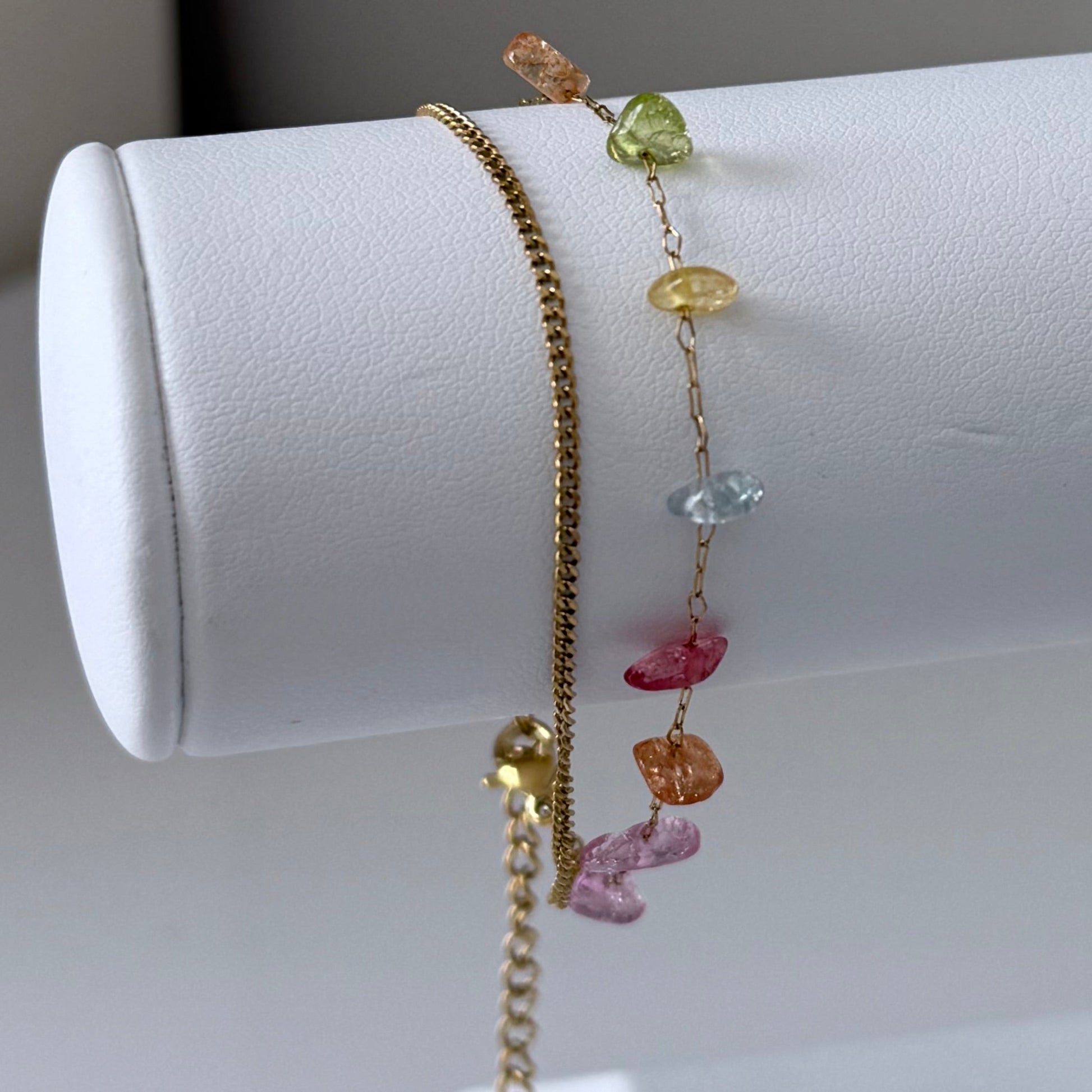 Bracelet with colorful gemstones on a white cylindrical stand