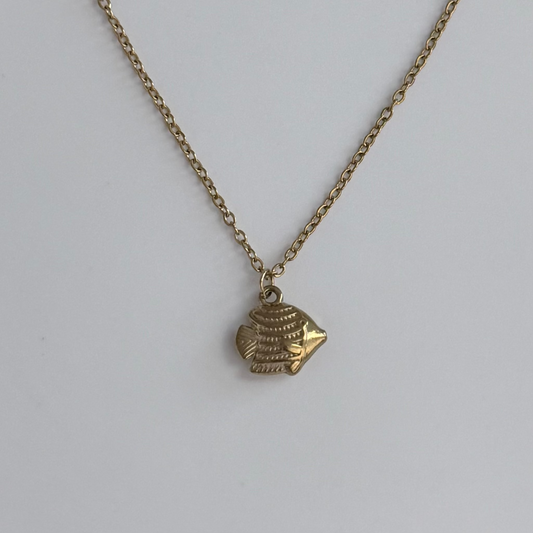 A gold-toned chain necklace with a small fish-shaped pendant, photographed against a plain light gray background.