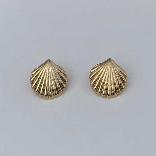 A pair of small gold-toned shell-shaped stud earrings with a ribbed texture, displayed on a plain light gray background.